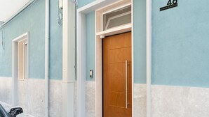 A building with a light blue exterior, a wooden door, and a small window.