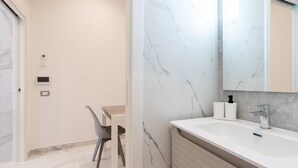 A bathroom with a marble sink, a mirror, and a toilet.