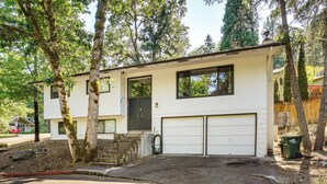 A modern two-story house with a garage, surrounded by trees. - 3 Mi to U of O Pet-friendly Home w/ Covered Deck! (Eugene)