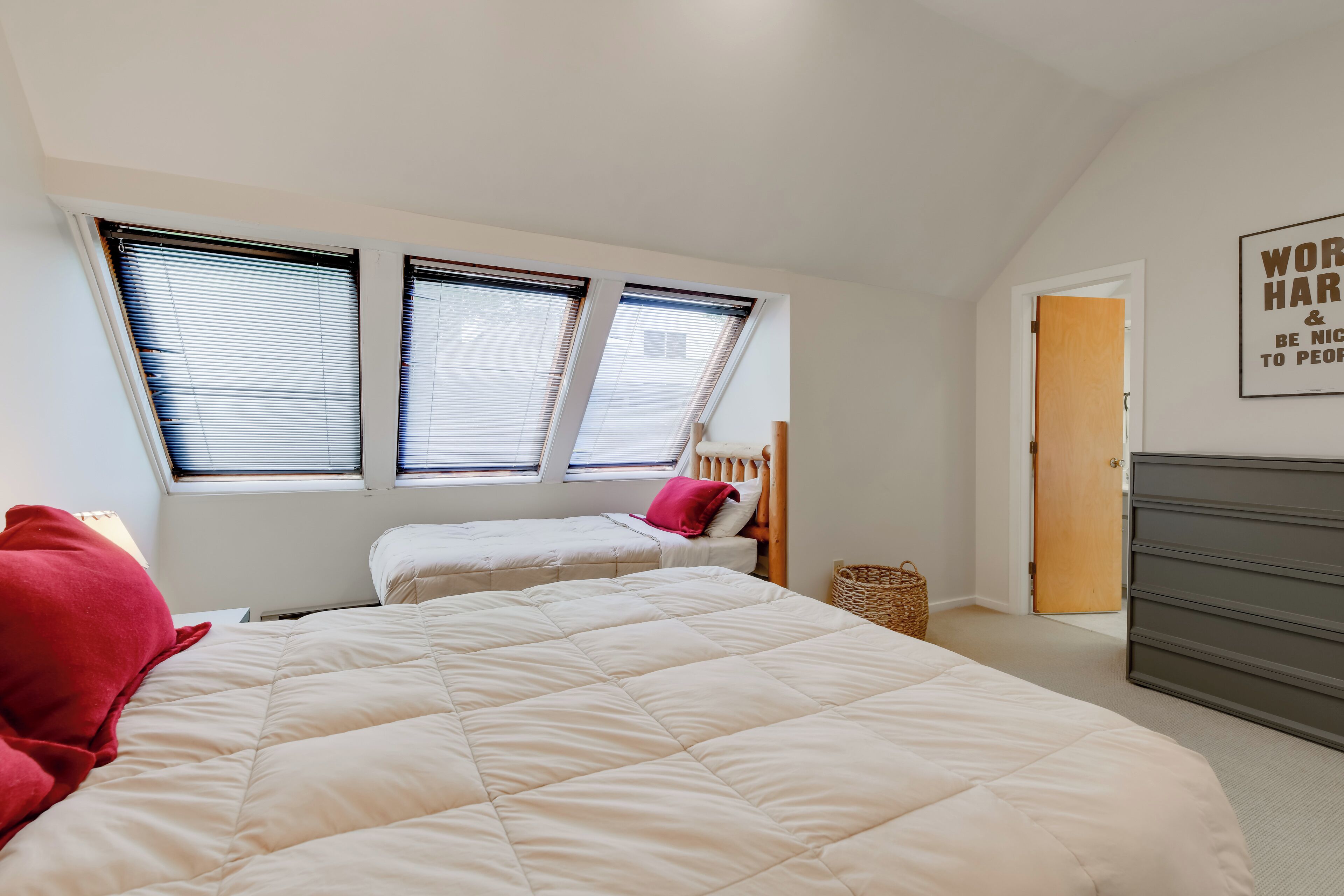 A bedroom with a large bed, a smaller bed, and a window with blinds.