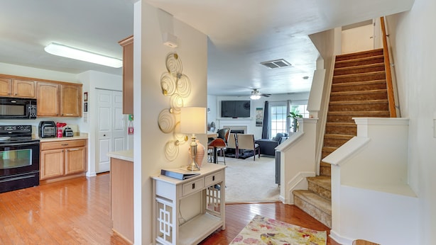 A spacious kitchen with wooden cabinets, a microwave, and a dining area with a table and chairs. - 6 Mi to Dtwn Raleigh: Townhome w/ Fenced Patio! (Raleigh)