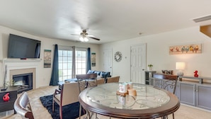 A living room with a fireplace, a round glass table, and a ceiling fan. - 6 Mi to Dtwn Raleigh: Townhome w/ Fenced Patio! (Raleigh)