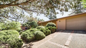 A residential property with a paved driveway, a garage, and well-maintained landscaping including bushes and trees. - Walkable Location! Extended Escape in Sedona (Sedona)