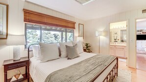 A bedroom with a large bed, bedside lamps, a window with blinds, a nightstand, and a view of the bathroom. - Walkable Location! Extended Escape in Sedona (Sedona)