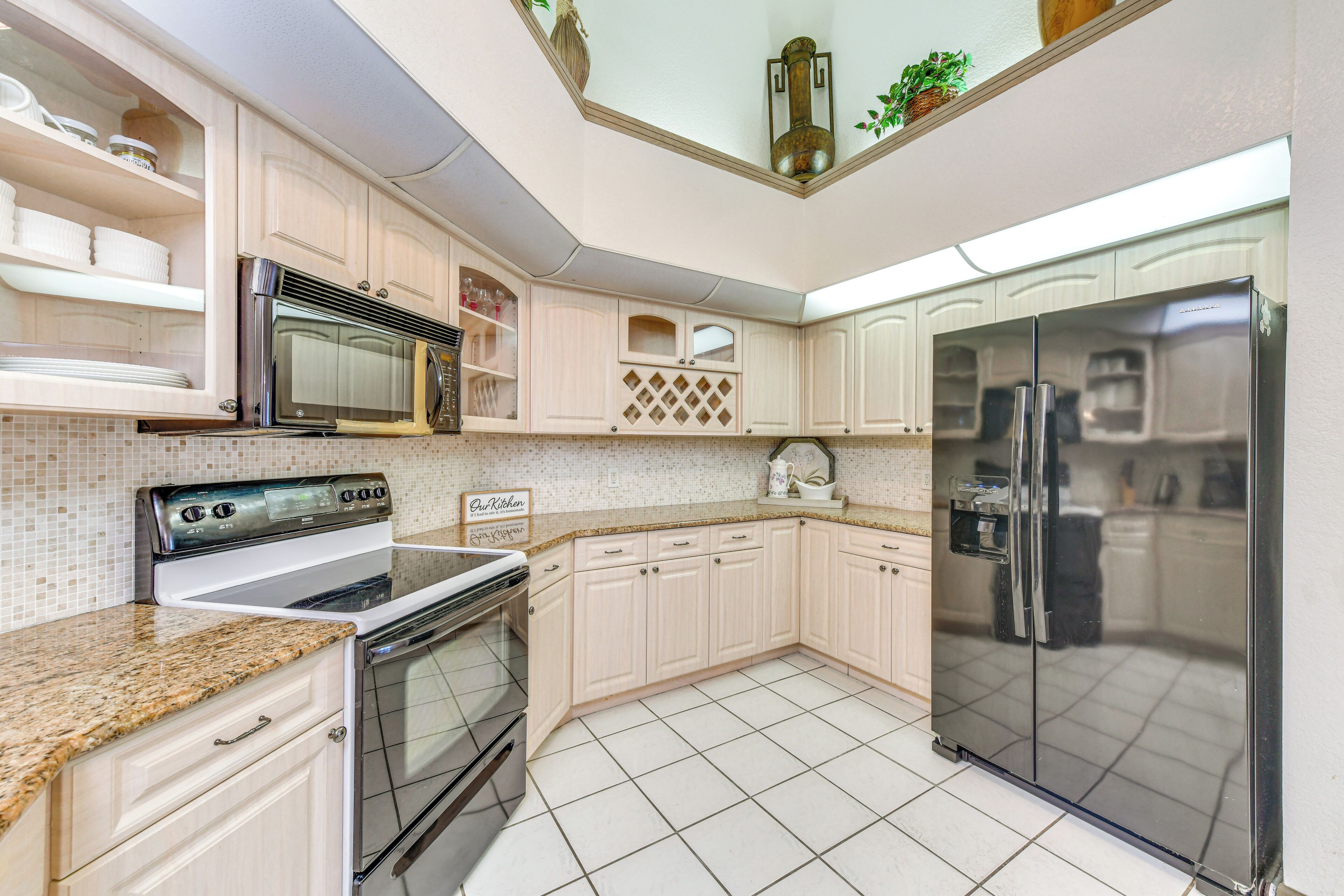 A kitchen with white cabinets, a stainless steel refrigerator, a microwave, and a stove.