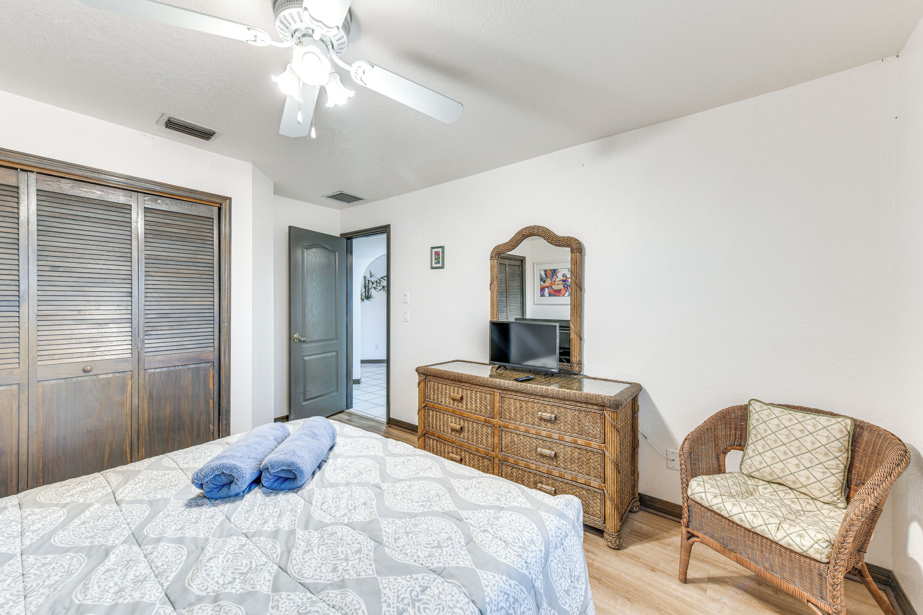 Ein Schlafzimmer mit Bett, Kommode, Stuhl, Deckenventilator und einer Tür.