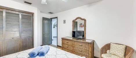 Ein Schlafzimmer mit Bett, Kommode, Stuhl, Deckenventilator und einer Tür.