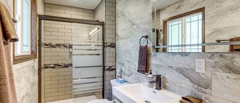 A modern bathroom with a glass-enclosed shower, a white toilet, and a marble backsplash.