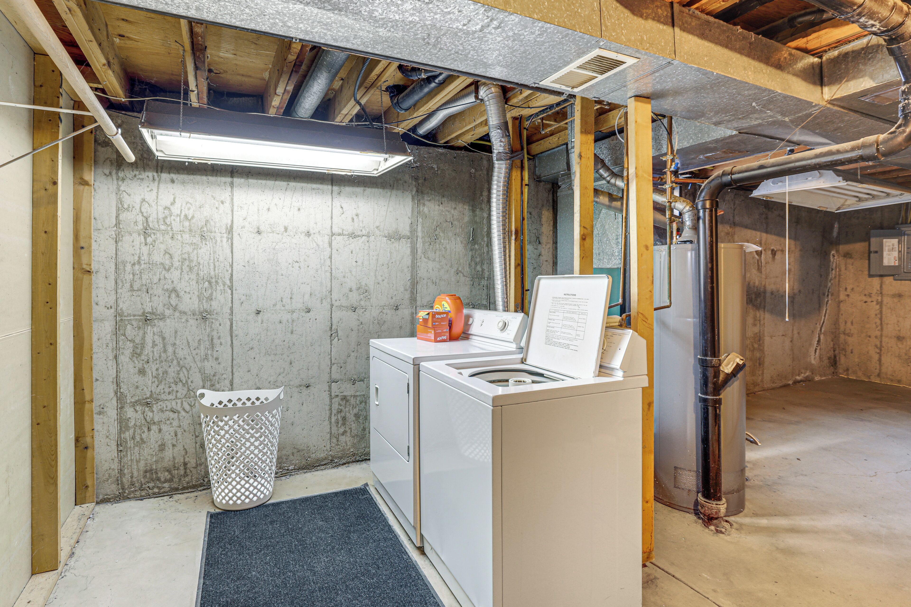 A laundry area with a washing machine, dryer, and a utility room with exposed ductwork and a water heater.