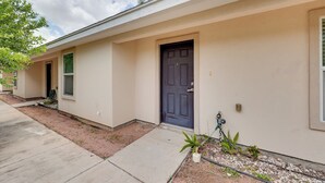 A single-story building with a dark front door, a small porch area, and a concrete pathway leading to the entrance.