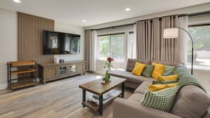 Una sala moderna con sofá, mesa de centro, televisor y un mueble de madera.