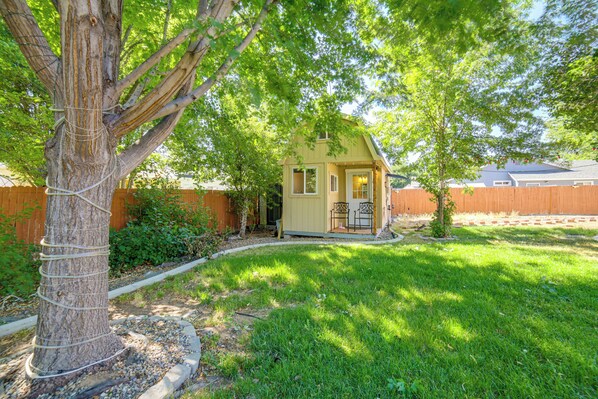 A small, single-story house with a front porch, surrounded by a wooden fence and a tree. - Cozy Tiny Home: 1 Mi to The Village at Meridian (Meridian)