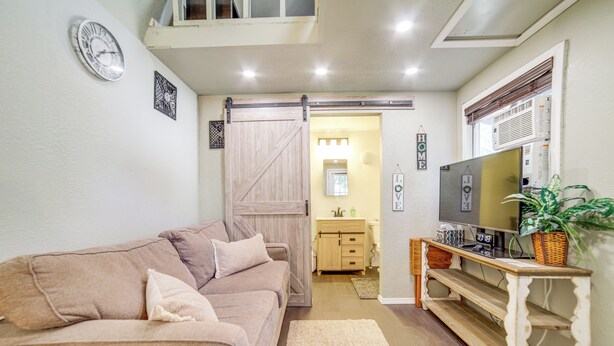 A living room with a sofa, TV, and a sliding door leading to a bathroom.