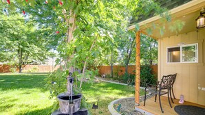 A patio area with a wooden deck, a small seating area with chairs, and a garden with a tree and a water feature.