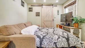 A bedroom with a bed, a sofa, a TV, and a sliding door.