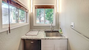 A compact kitchen with a built-in dishwasher, a sink, and a window above it.