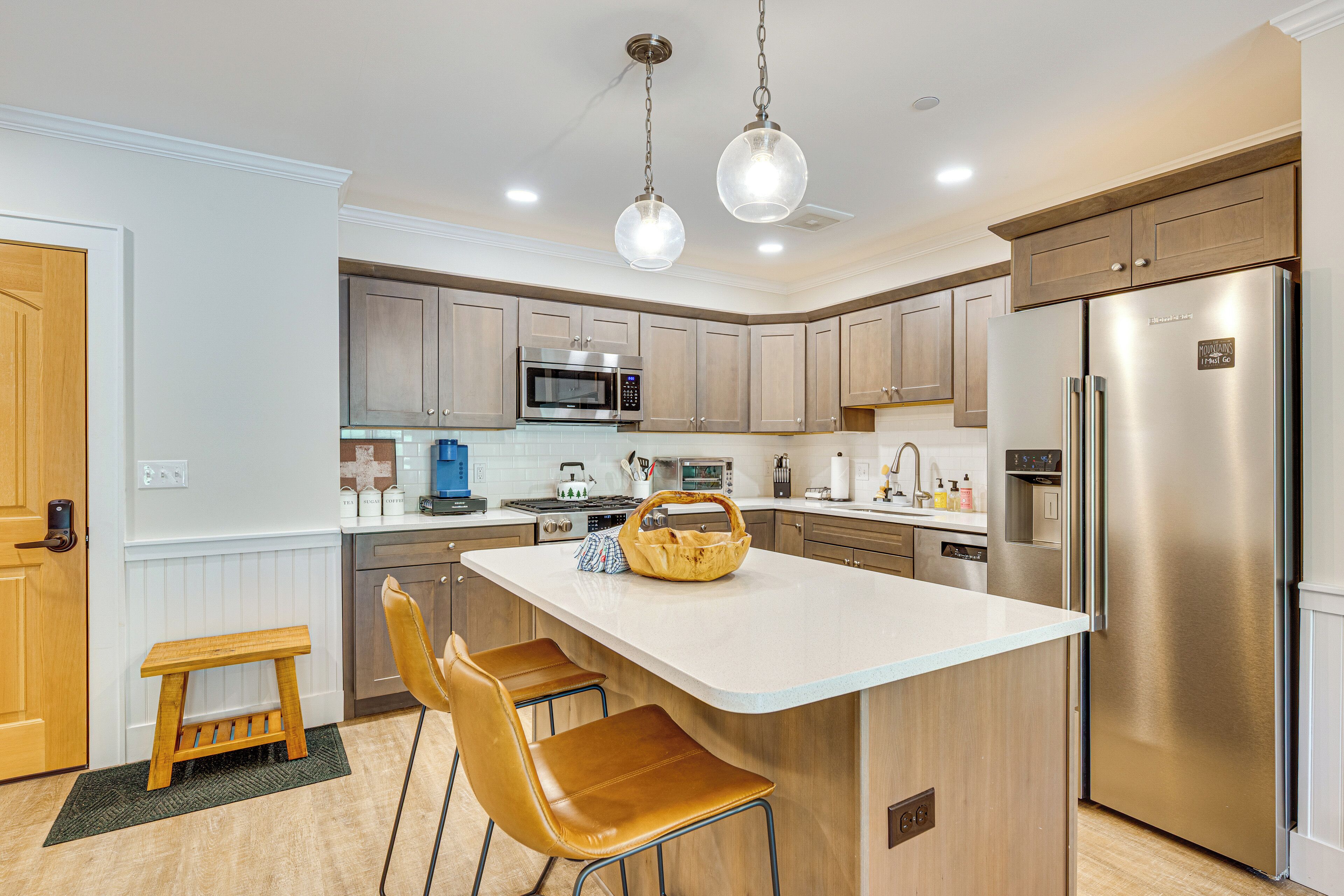 A modern kitchen with a central island, stainless steel appliances, and wooden cabinetry.