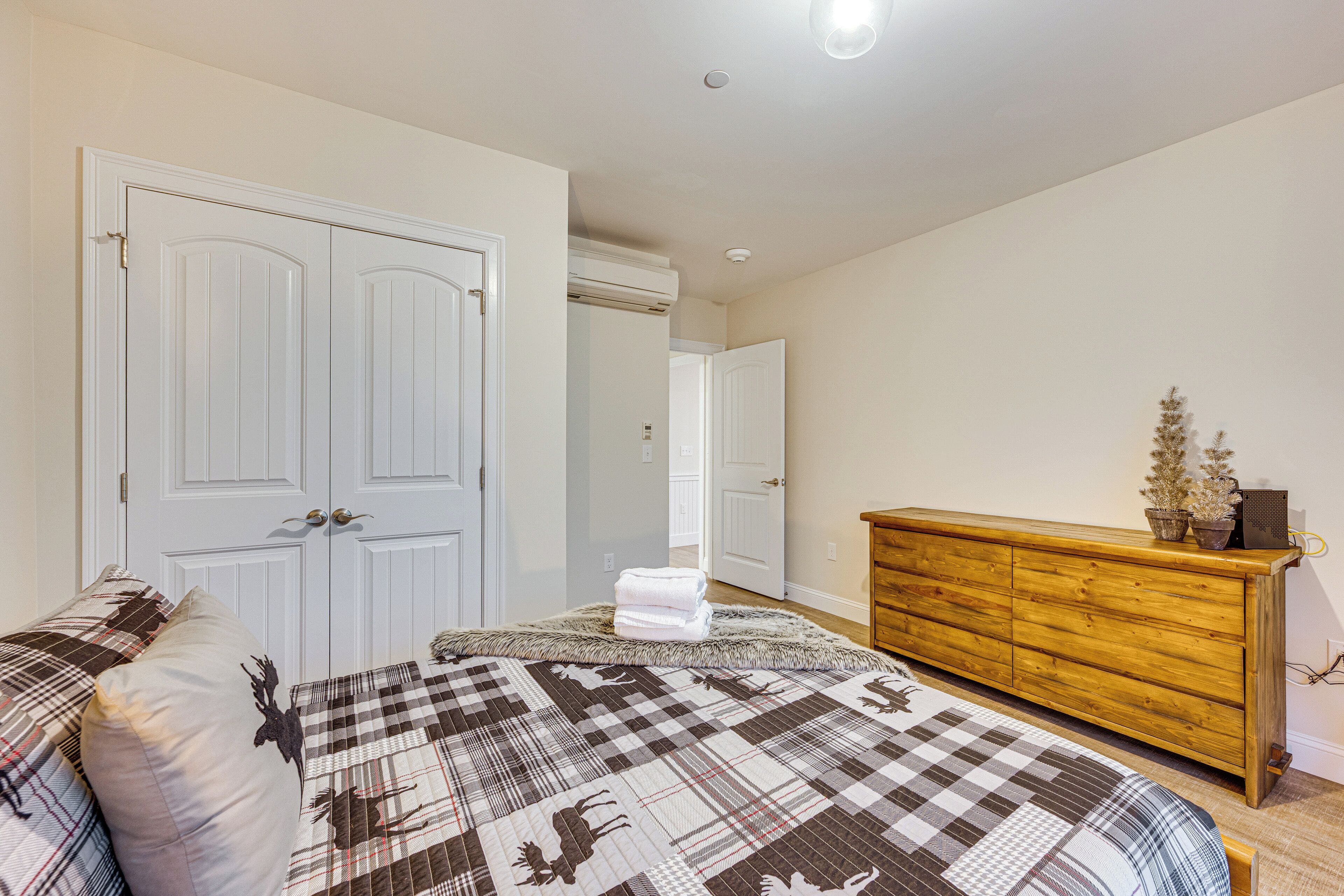 A bedroom with a bed, a wooden dresser, and a white door.