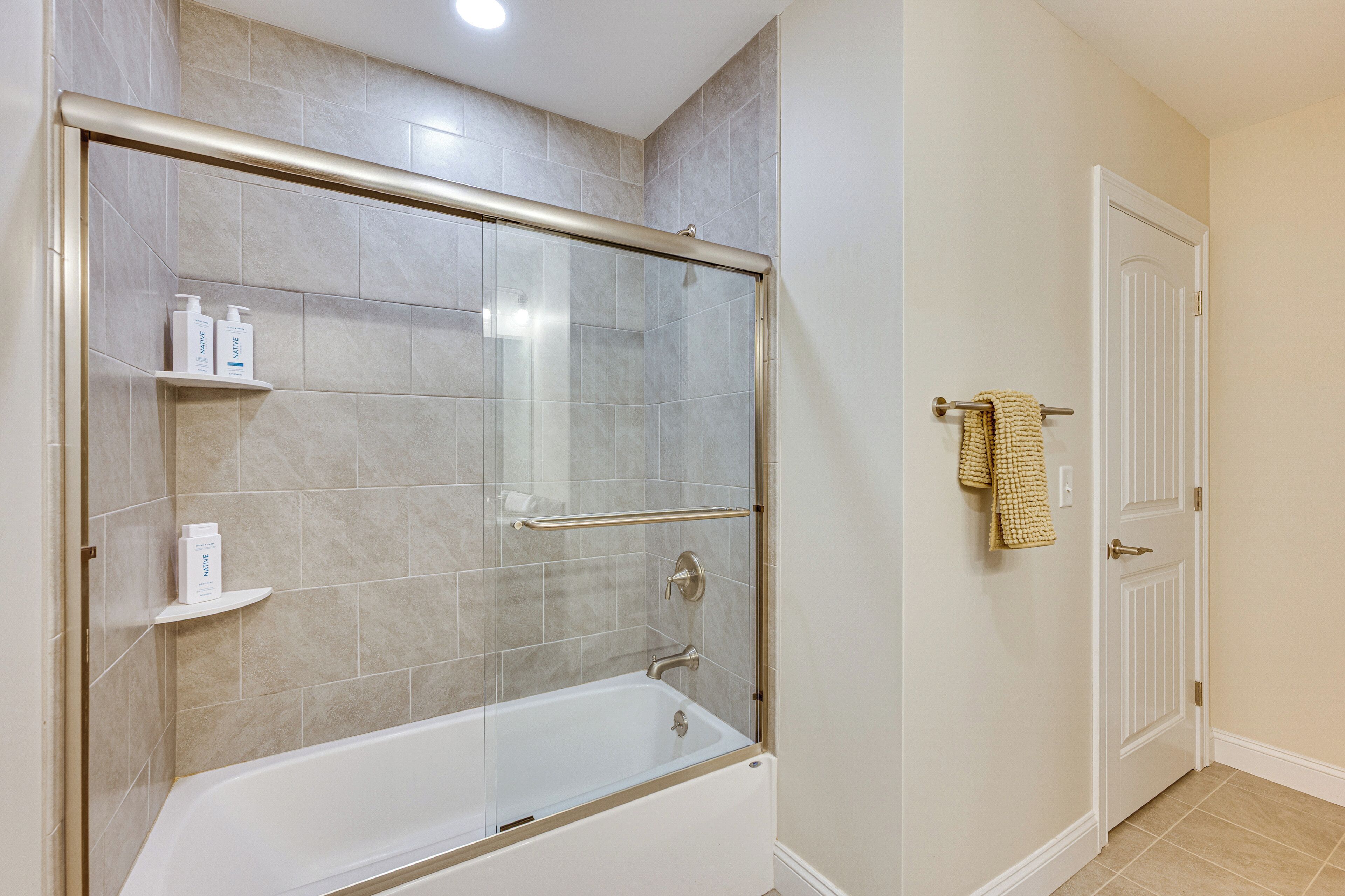 Une salle de bain avec une douche à parois de verre, une baignoire blanche et un porte-serviettes avec une serviette.