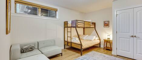 Un dormitorio con una cama litera, un sofá, una mesita de noche y una puerta.