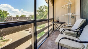 A balcony with a view of a park and a building, furnished with two chairs and a small table. - Lake Access & Community Pool: Cozy Condo in Mound (Mound)