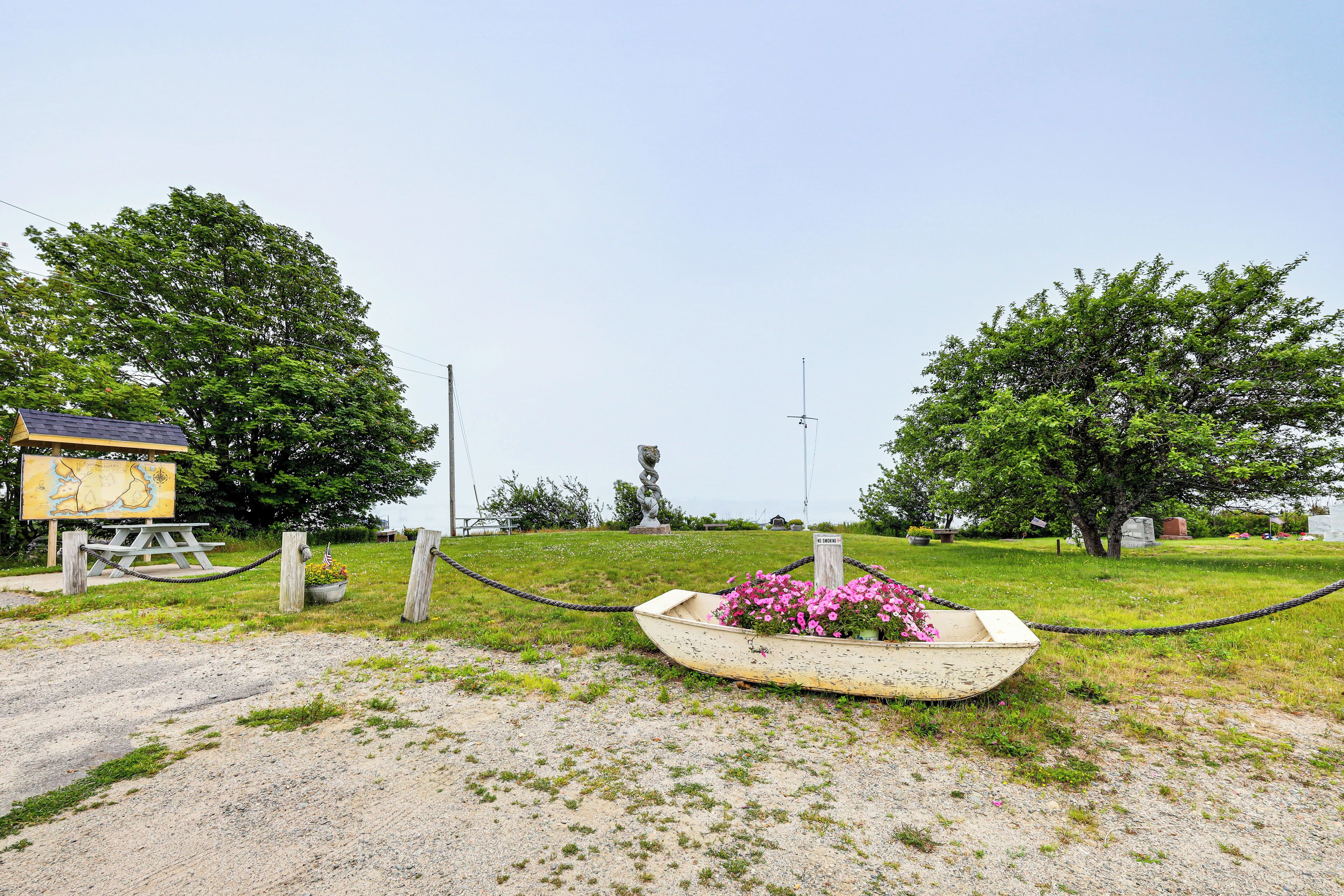 A boat with pink flowers, a wooden sign, and a grassy area with trees.