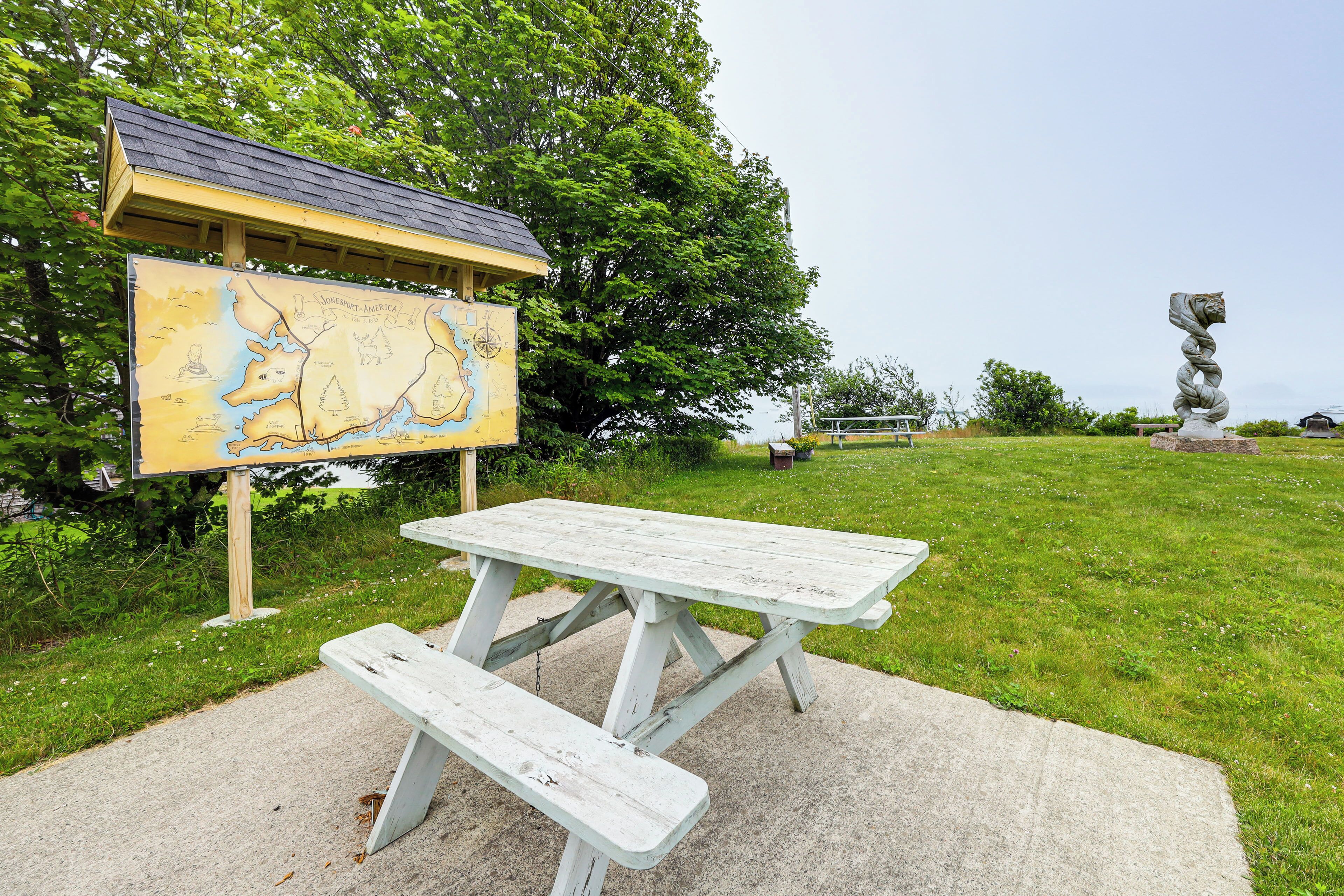A picnic table and a map sign in a park.