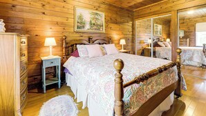 Quarto com painéis de madeira, uma cama grande, uma mesa de cabeceira, um penteado e um espelho.