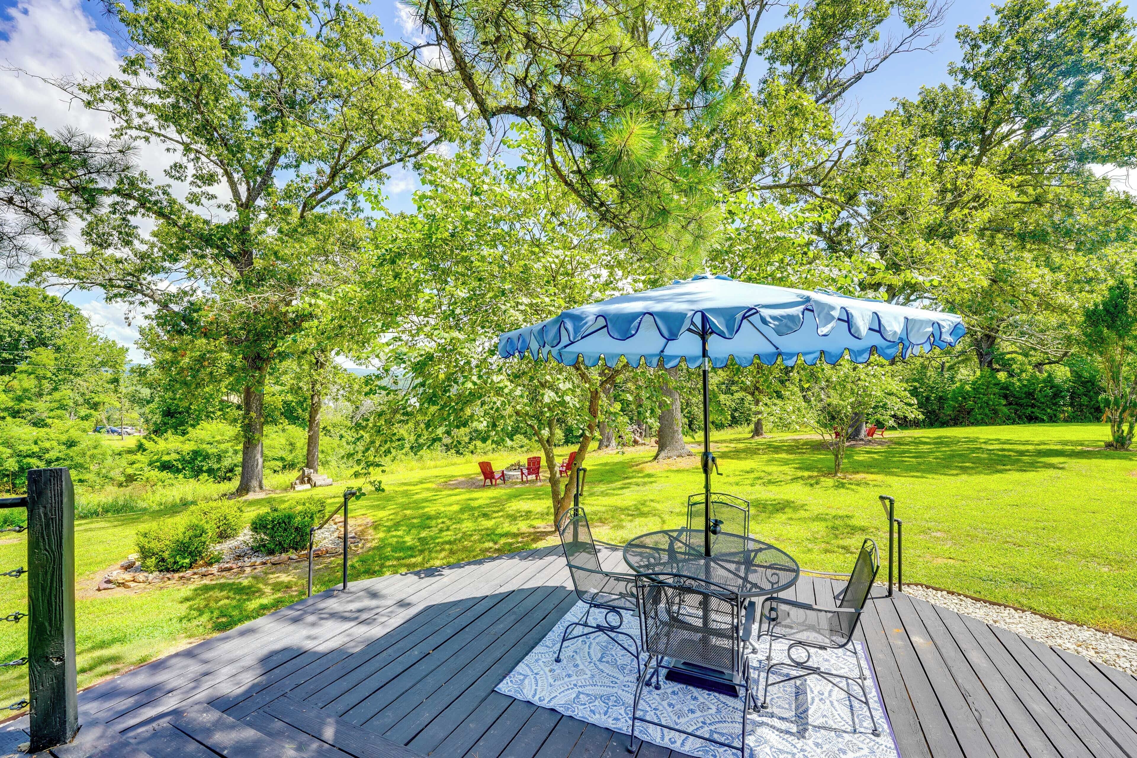 Een terras met tuinmeubilair, een oploop van een tapijt en een blauwe parasol.