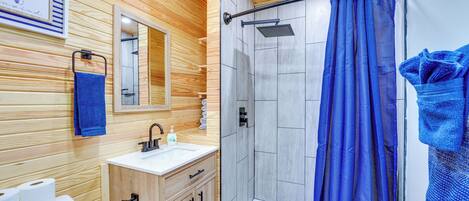 A wooden-paneled bathroom with a shower, a sink, and a toilet.