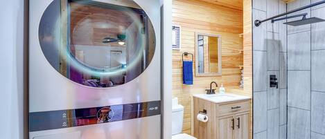 Un baño moderno con un espejo circular, inodoro, lavabo y zona de ducha.