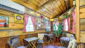 A rustic interior with wooden walls, checkered curtains, and a vintage Coca-Cola sign. - Tiny Home w/ Private Sauna in Woods of Newport! (Newport)