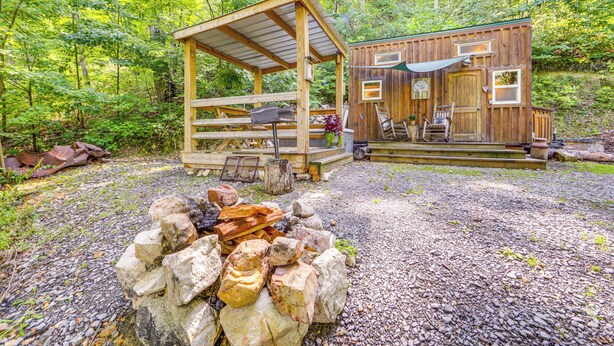 A rustic cabin with a wooden deck and a fire pit in the foreground. - Tiny Home w/ Private Sauna in Woods of Newport! (Newport)