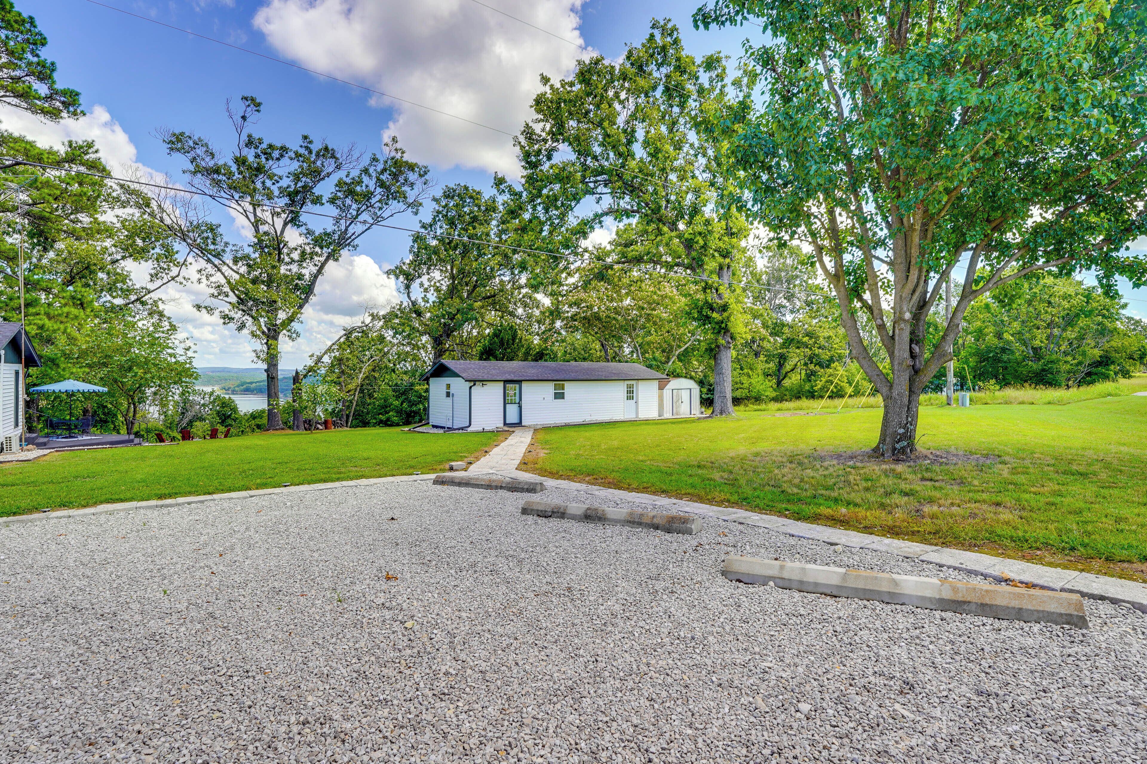 A small, single-story house with a gravel driveway and a grassy lawn.