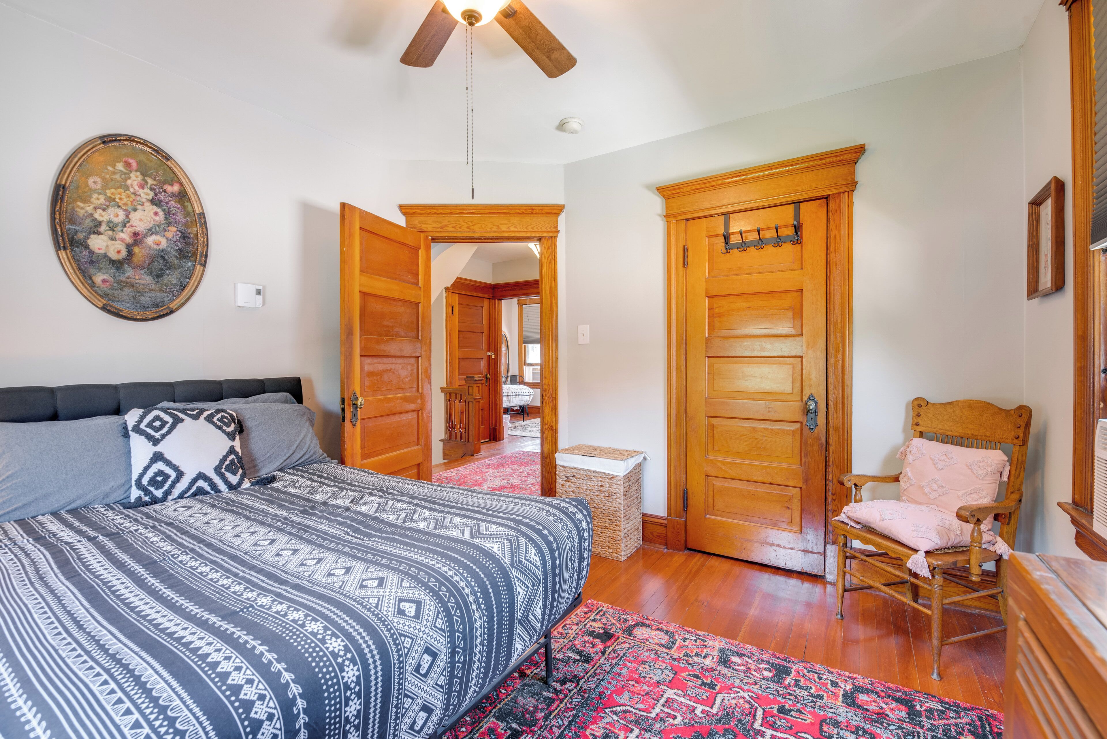 Ein Schlafzimmer mit einem Bett, einem Sessel, einem Holzschrank und einem Deckenventilator.