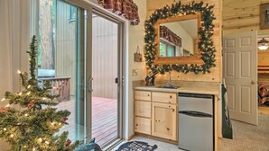 A kitchen with a refrigerator, a wooden cabinet, and a Christmas tree with lights. - Game Room & Deck: Pet-friendly Camp Connell Cabin (Arnold)