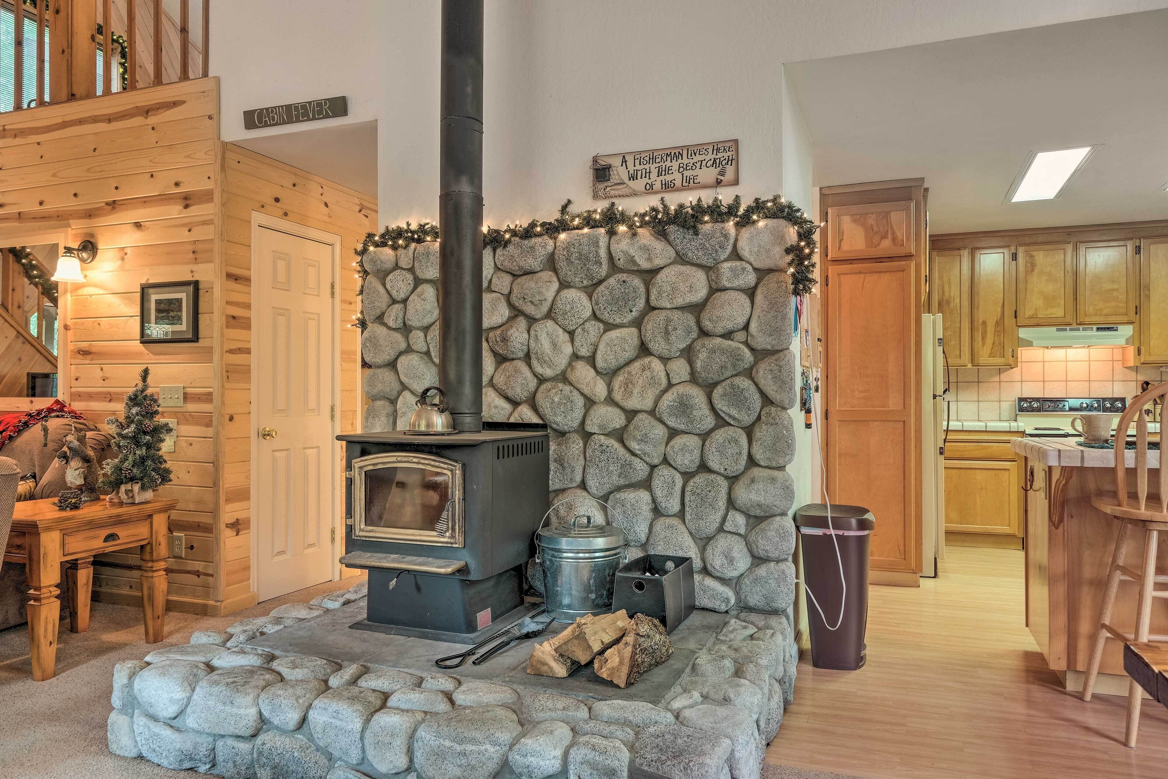 L’intérieur d’une cabane avec un mur en pierre, une porte en bois, une cheminée et un coin cuisine.