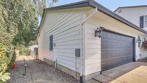 Une maison d’habitation avec un garage, un chemin bordé de galets et un lampadaire en métal.