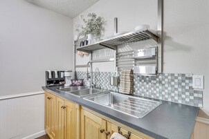 Cozinha moderna com duas pias de aço inoxidável, armários de madeira, painel de azulejos e exaustor de aço inoxidável.