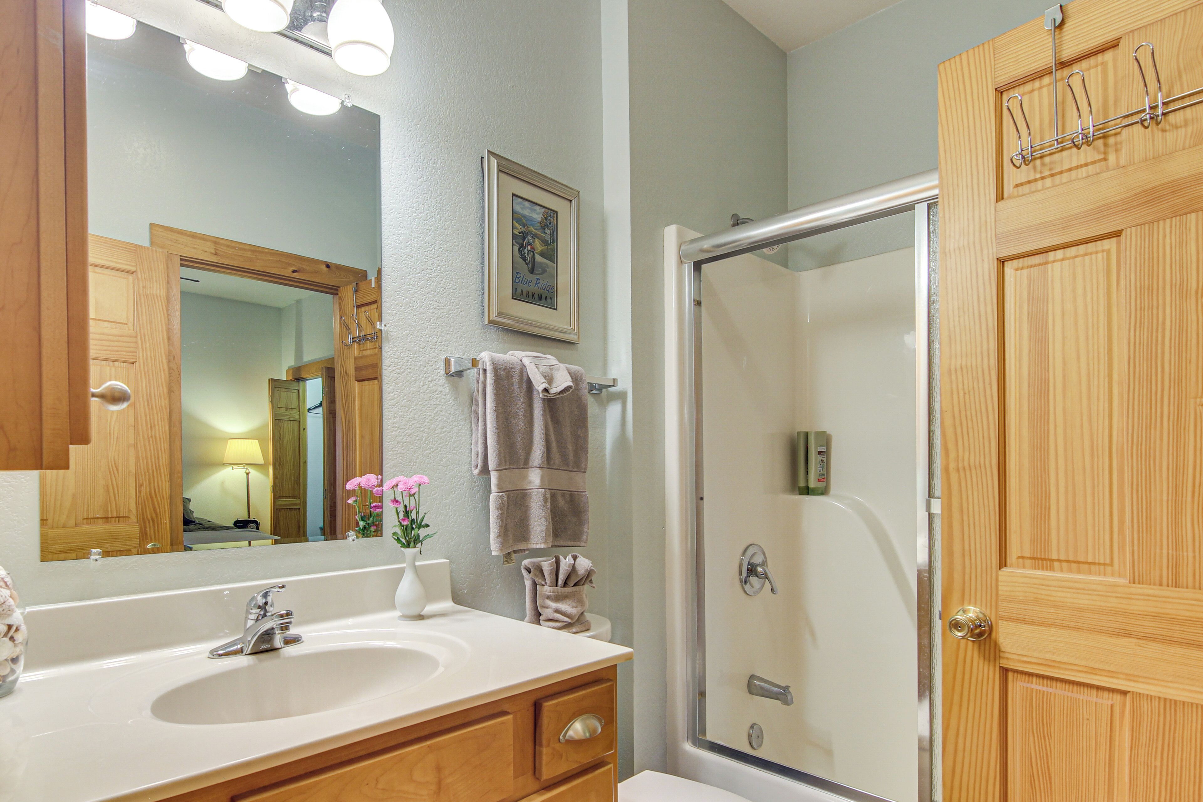 A bathroom with a sink, mirror, and shower.