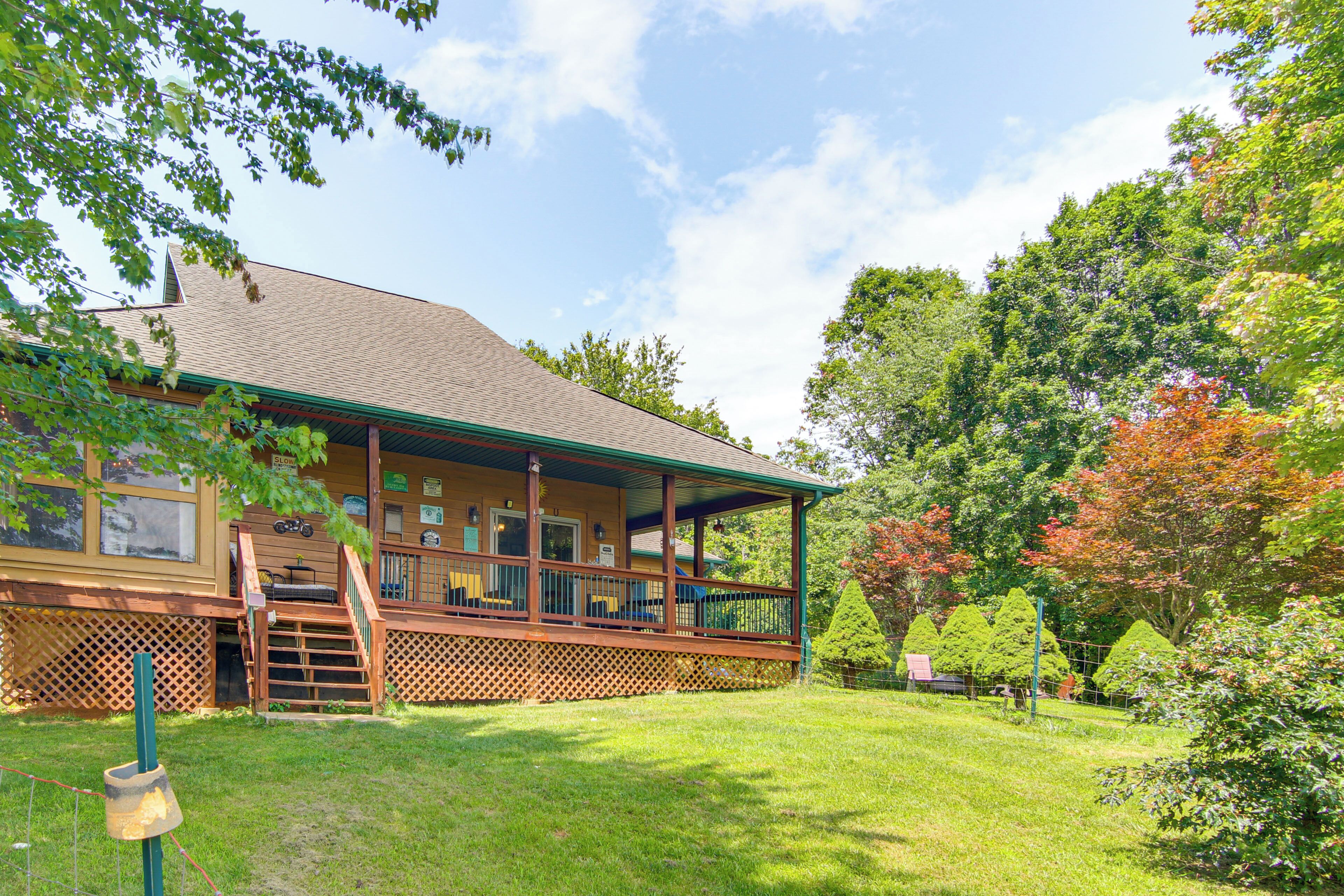 A lodge with a covered porch, wooden deck, and a well-maintained lawn.