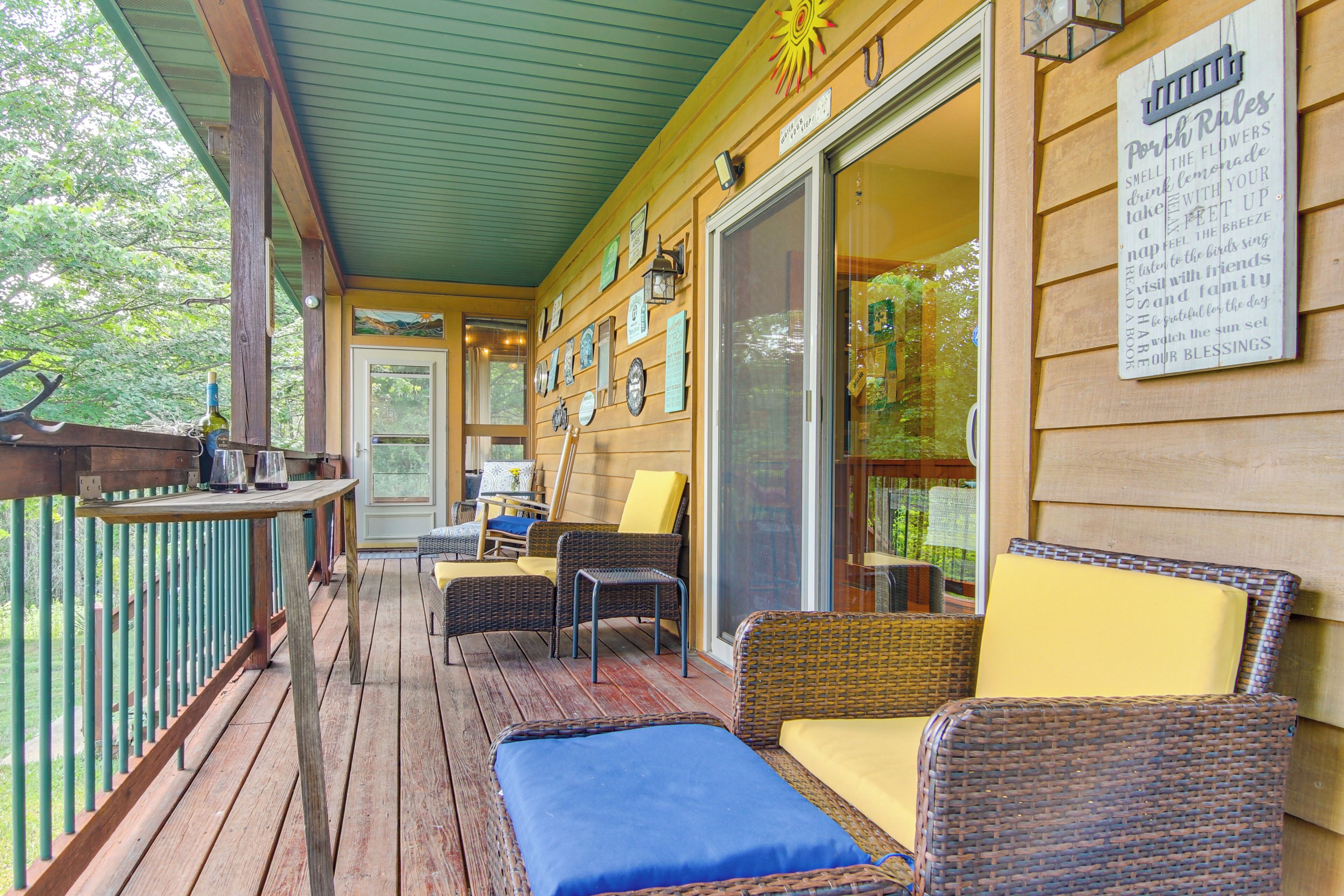 A wooden deck with wicker furniture, a table, and a sign listing porch rules.