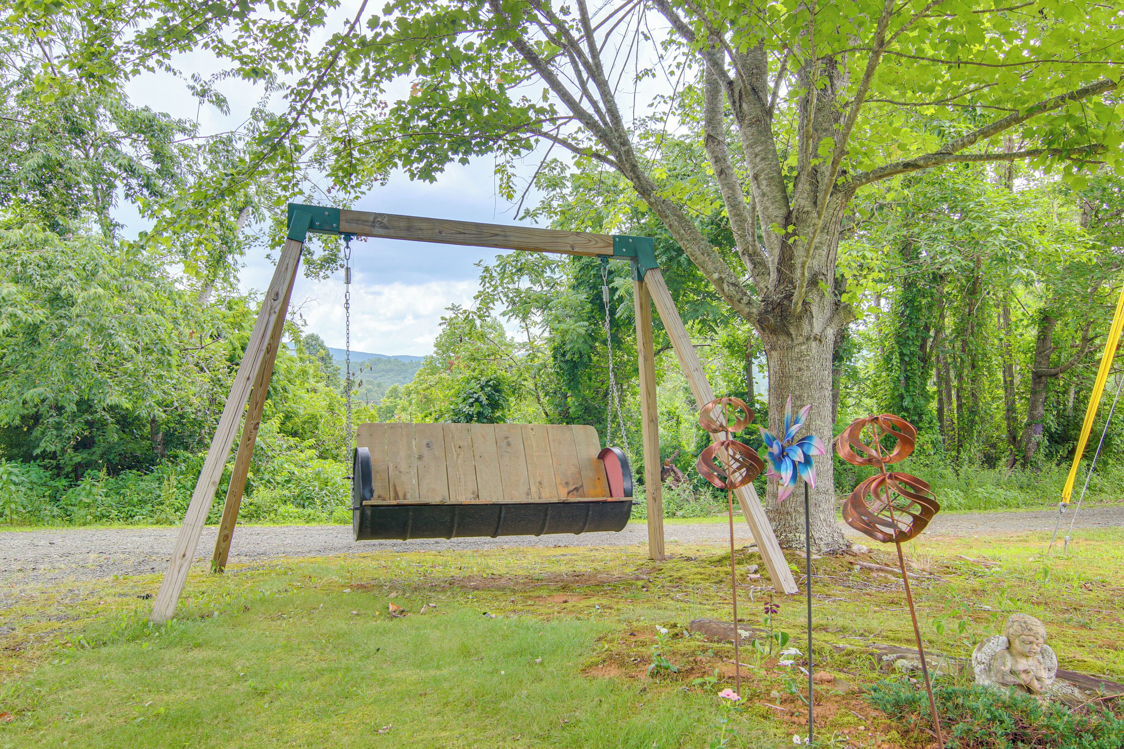 A wooden swing set in a wooded area with a grassy ground.