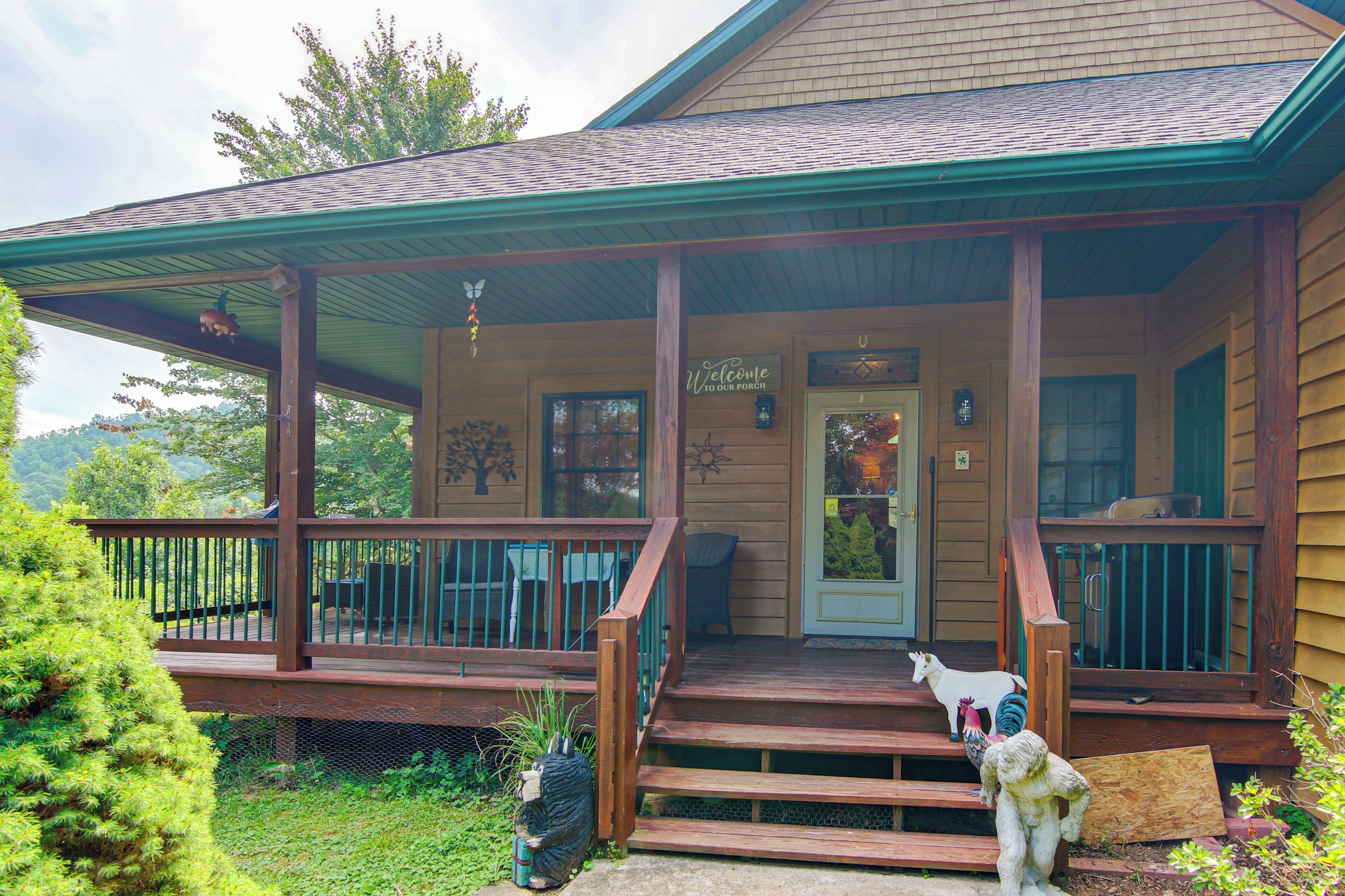 A wooden house with a porch, a welcome sign, and a small dog statue.
