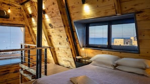 A wooden cabin room with a bed, a window with blinds, a small table, and a ladder leading to an upper level. - A-home Villa Private Pool Relaxing Hottub Oasis (Heraklion)