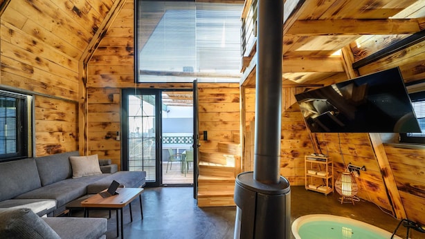 A cozy cabin interior with a sofa, a table, a fireplace, and a television. - A-home Villa Private Pool Relaxing Hottub Oasis (Heraklion)