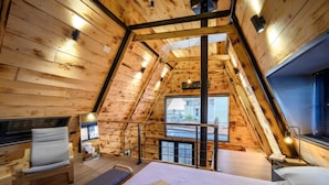 A cozy attic bedroom with wooden walls, a bed, a chair, and a window with a view. - A-home Villa Private Pool Relaxing Hottub Oasis (Heraklion)