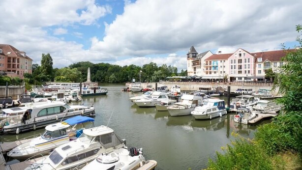 A marina with various boats docked, a bridge, and buildings with a mix of architectural styles. - Le Riviera - Port Cergy | Modern & Cosy (Port-Cergy)