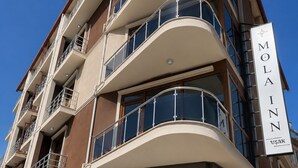 A multi-story hotel with balconies, a sign reading 'MOLA Inn,' and a clear blue sky.
