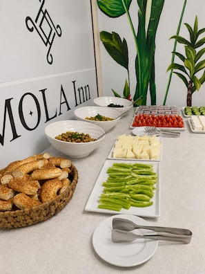 A buffet table with various food items, a sign with 'MOLA Inn' text, and decorative plants. - Mola Inn Uşak (Uşak)